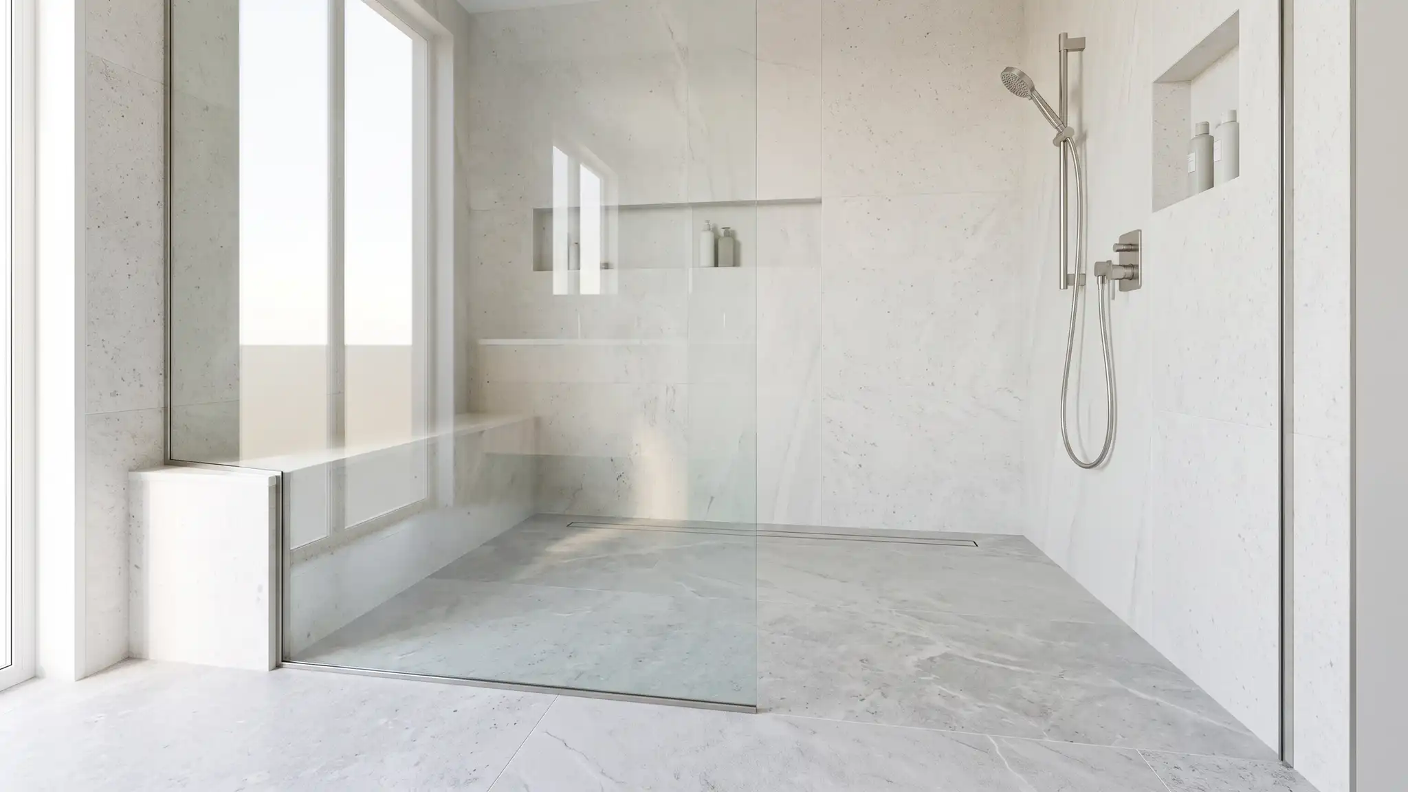 A bright curbless walk-in shower with a wide clear glass panel, a built-in bench, a handheld shower and a flush floor